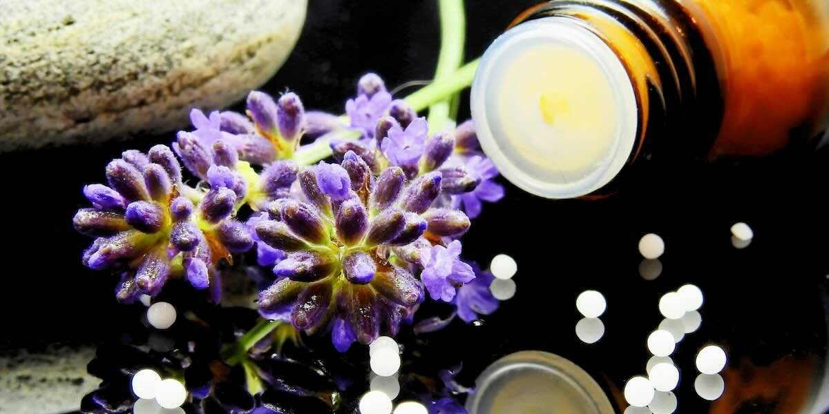 Fiori viola e granuli omeopatici, rappresentanti la medicina olistica.